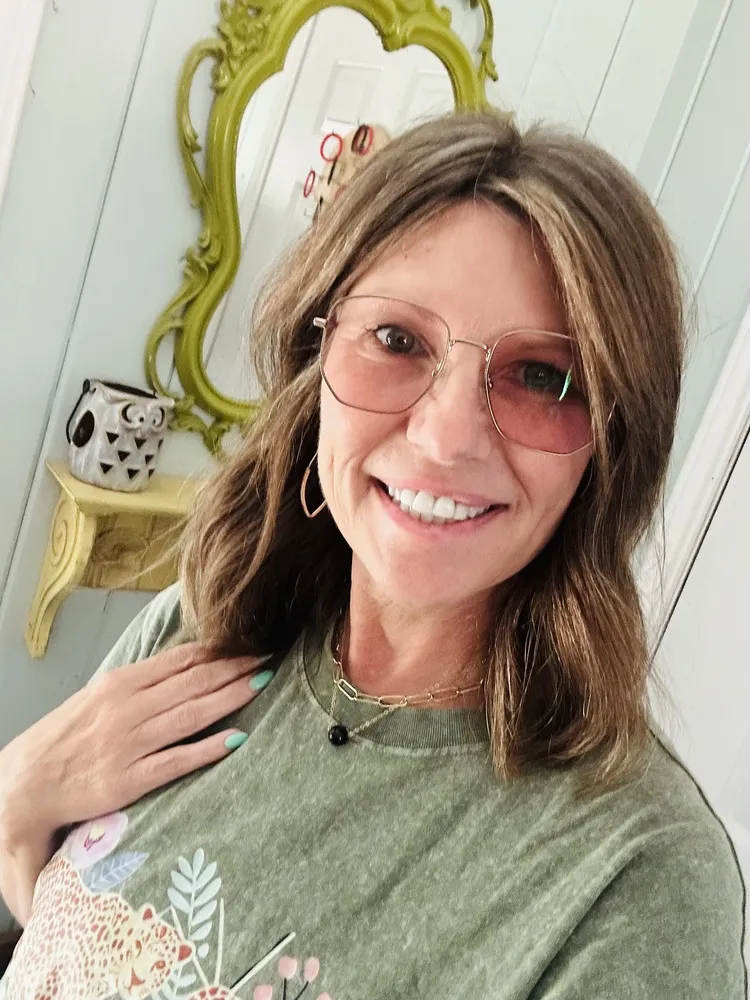 Amanda smiling in LOOK OPTIC Gina frames with gold rims and pink-tinted lenses
