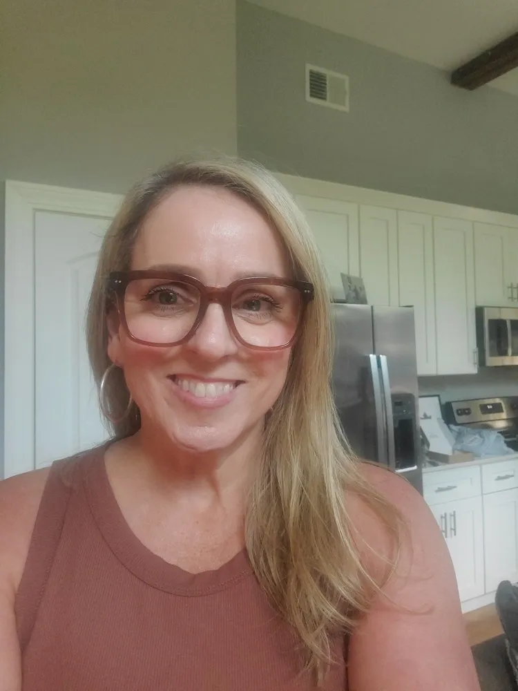 Amy smiling in LOOK OPTIC Laurel readers in Shiny Cinnamon, standing in her kitchen