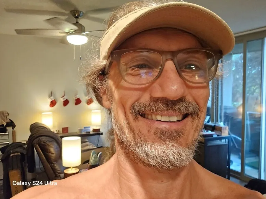 Damon smiling in LOOK OPTIC Sullivan progressives in taupe, wearing a visor at home
