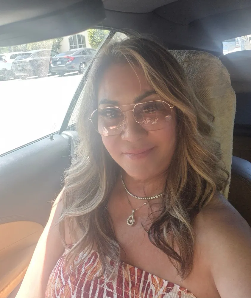Eleanor wearing LOOK OPTIC Muse Progressives with gold-rimmed frames, in a car