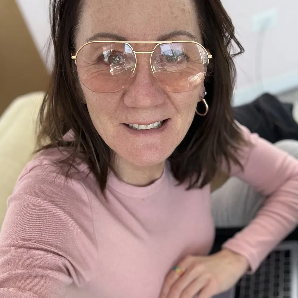 January wearing LOOK OPTIC Muse Progressives with gold-rimmed frames, seated indoors