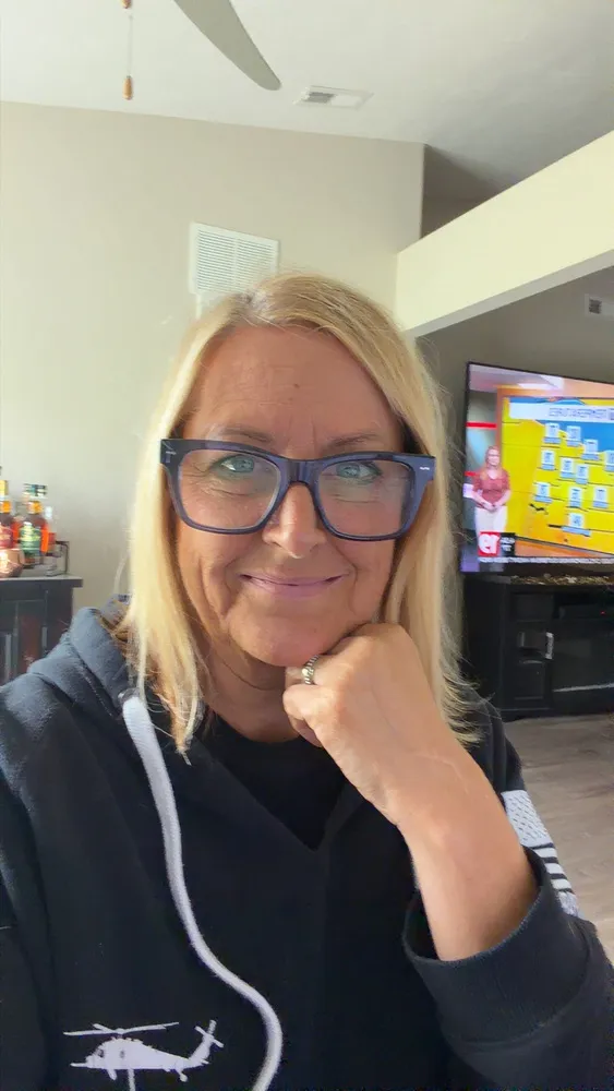 Jeannie wearing LOOK OPTIC Cosmo readers in Shiny Grey Blue, chin resting on her hand at home