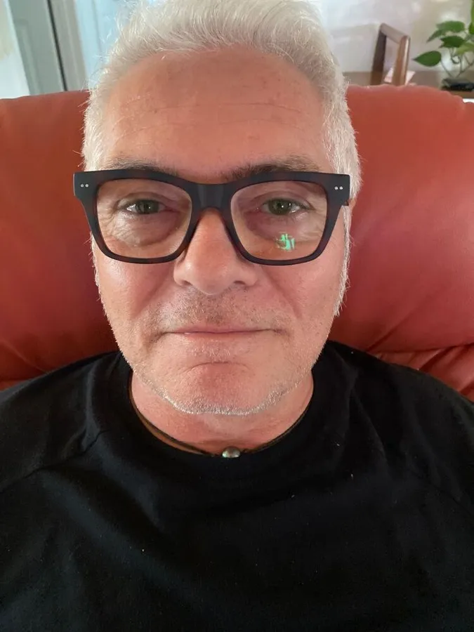 John wearing LOOK OPTIC Cosmo readers in tortoise, seated in an armchair