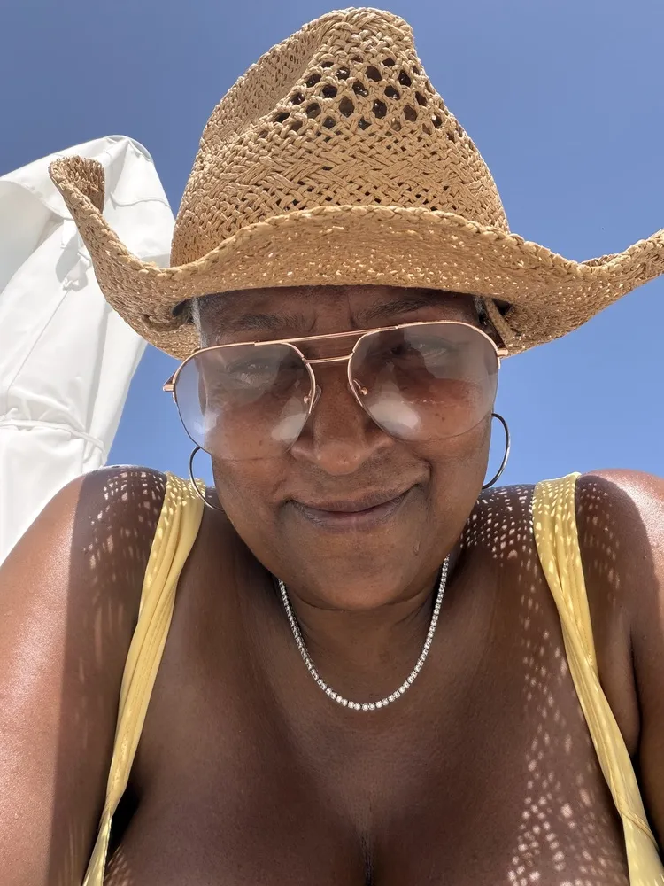 Lisa in a straw cowboy hat wearing tinted LOOK OPTIC frames on a sunny day