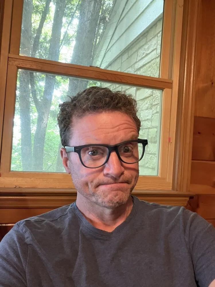 Tom wearing LOOK OPTIC Sullivan Progressives with black frames, standing by a window